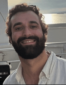 a man with a beard wearing a white shirt and a necklace that says ' a ' on it