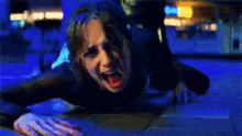 a woman is laying on the ground with her mouth open in a dark room .