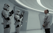 three stormtroopers are standing next to a man in a white suit