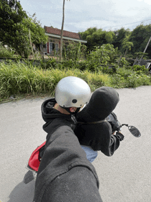 a man wearing a helmet and a black hoodie is riding a motorcycle