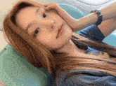 a woman wearing a watch is laying on a chair with her hand on her face