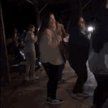 a group of people are dancing in a dark area