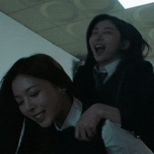 a woman in a suit and tie holds another woman on her back and smiles