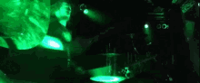 a man is playing a guitar on stage in a dark room with green lights .