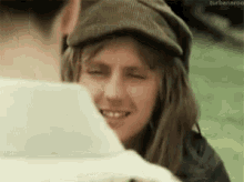 a woman wearing a hat is smiling and looking at another woman .