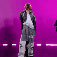 a man is dancing in front of a purple background .