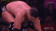 a man is kneeling down in front of a crowd during a wrestling match on a tv screen .