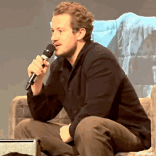 a man in a black shirt is holding a microphone