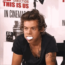 harry styles is sitting in front of a sign that says " this is us in cinema "