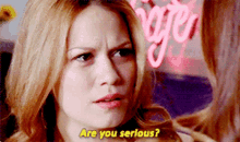 a woman says are you serious in front of a neon sign that says rage