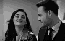 a black and white photo of a man and woman looking at each other .