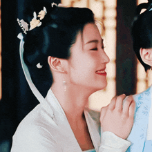 a woman with a flower in her hair is smiling and holding another woman 's arm