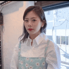 a woman wearing a white shirt and a blue apron has red lipstick on her lips