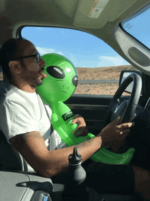 a man in a car with a green inflatable alien that says fusion