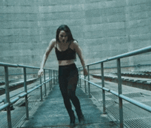 a woman in a black crop top is running down a set of stairs