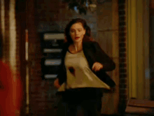 a woman in a black jacket is running down a hallway at night .