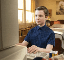 a young boy is typing on a keyboard in front of a computer
