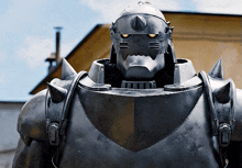 a statue of a robot with a helmet on stands in front of a house