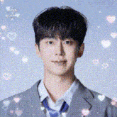 a young man in a suit and tie is surrounded by hearts and sparkles .