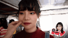 a woman 's face is being touched with a red sticker that says ' o ' on it