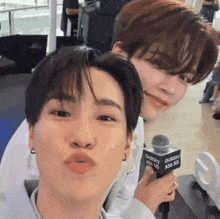 two young men are posing for a picture with a microphone that says galaxy a54 5g .