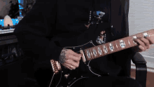 a man with a tattoo on his arm is playing an electric guitar .