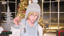 a man wearing a white hat is holding a snowflake in front of a christmas tree with playe in the corner