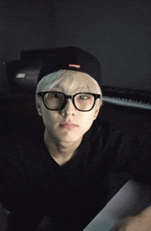 a young man wearing glasses and a hat with supreme on it
