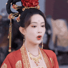 a woman in a red and gold costume with a red flower in her hair