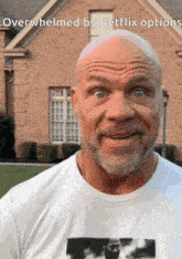 a bald man with a beard is standing in front of a brick house with the words overwhelmed by netflix options below him