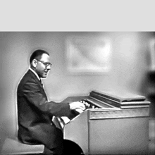 a man in a suit and tie is playing a piano