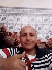 a bald man is sitting in front of a tiled wall holding a glass of wine .