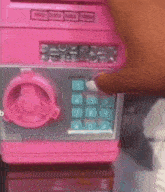 a person is pressing the number 1 button on a pink and silver machine