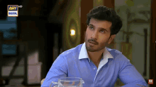a man in a blue shirt is sitting at a table with a pitcher of water and says ary digital on the bottom