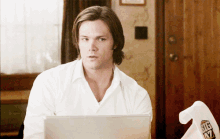 a man in a white shirt is using a laptop with a big 17 t-shirt in front of him