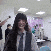 a woman in a plaid shirt and tie is smiling in a room