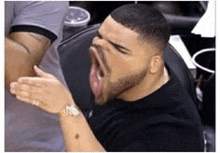 a man with a beard is sitting in a chair with his mouth open .