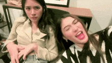 two women are sitting next to each other on a couch .