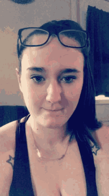 a woman wearing glasses and a tank top has a star tattoo on her arm