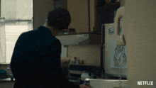 a man standing in a kitchen next to a refrigerator that has a sticker on it that says sunny