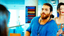 a man with a beard and a blue shirt is standing next to a woman in a room .