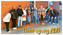 a group of people standing in front of a brick wall with the words thanksgiving 2021 written above them