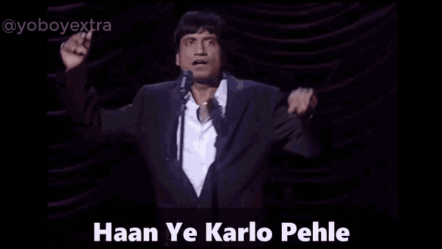 a man in a suit stands in front of a microphone with the words haan ye karlo pehle written below him