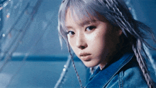 a close up of a woman 's face with a denim jacket on
