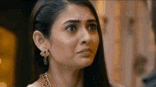 a close up of a woman wearing earrings and a necklace making a face .
