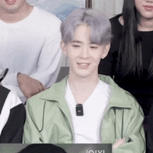 a man in a green jacket is sitting in front of a sign that says ioiyi
