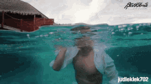 a shirtless man is swimming in the ocean with judleklek702 in the corner