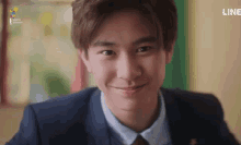 a young man in a suit and tie is smiling and looking at the camera