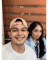 a man wearing a hat and braces smiles next to a woman