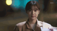 a close up of a woman holding a bouquet of flowers with kbs written on the bottom